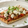 Einfaches Feta-Fladenbrot auf einem weißen Teller, frisch gebacken und weich, serviert auf Holztisch