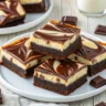 Frisch gebackene Cheesecake Brownies mit cremiger Käsekuchenschicht auf einem Holzbrett, in Stücke geschnitten