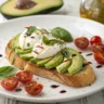 Frische Avocado-Burrata-Bruschetta mit knusprigem Ciabatta, cremiger Avocado, Burrata, Cherrytomaten und frischem Basilikum auf einem Holzbrett serviert