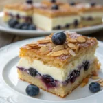 Bienenstich-Schnitten mit Heidelbeer-Creme auf einem Holzbrett, mit knusprigem Mandel-Honig-Topping und cremiger Heidelbeerfüllung
