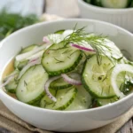 Omas Gurkensalat süß-sauer in einer rustikalen Schüssel, garniert mit frischem Dill und leichtem süß-sauren Dressing