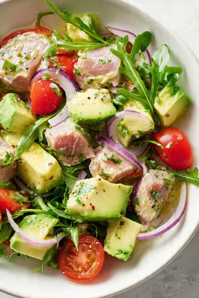 Frischer Thunfisch-Avocado-Salat in weißer Schüssel - proteinreiches Low Carb Rezept zum Abnehmen, fertig in 10 Minuten. Gesunder Salat mit Thunfisch, Avocado, Tomaten und Paprika